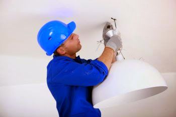 Electrician fitting a ceiling light